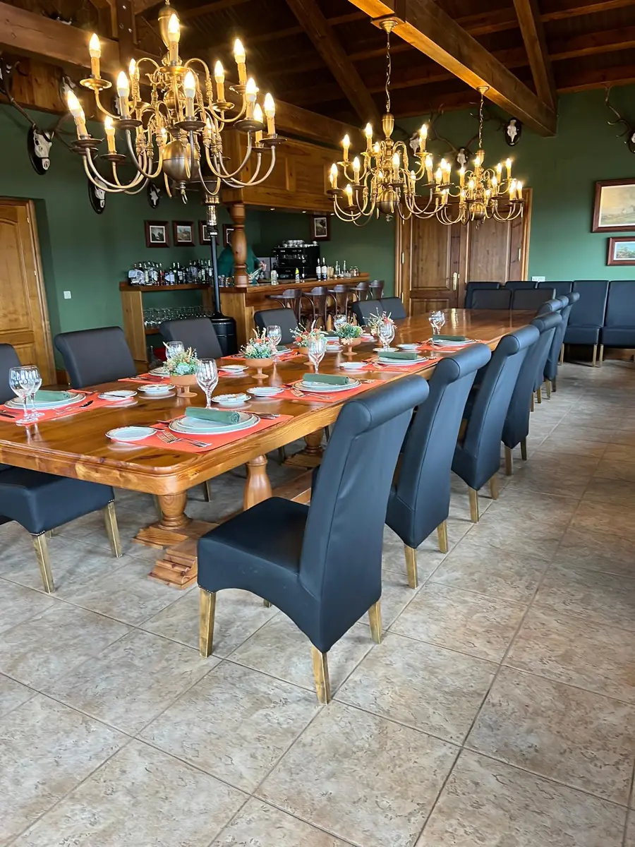 Long dining table laid for a shoot party beneath brass chandeliers at La Cuesta