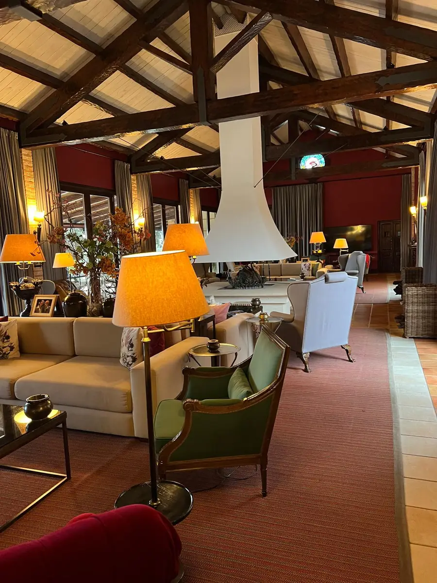 Open-raftered great hall at La Cuesta with a central fireplace, sofas and reading lamps