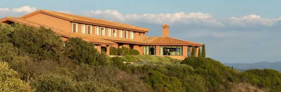 The terracotta-walled lodge at La Nava on a scrub-covered hillside in evening light