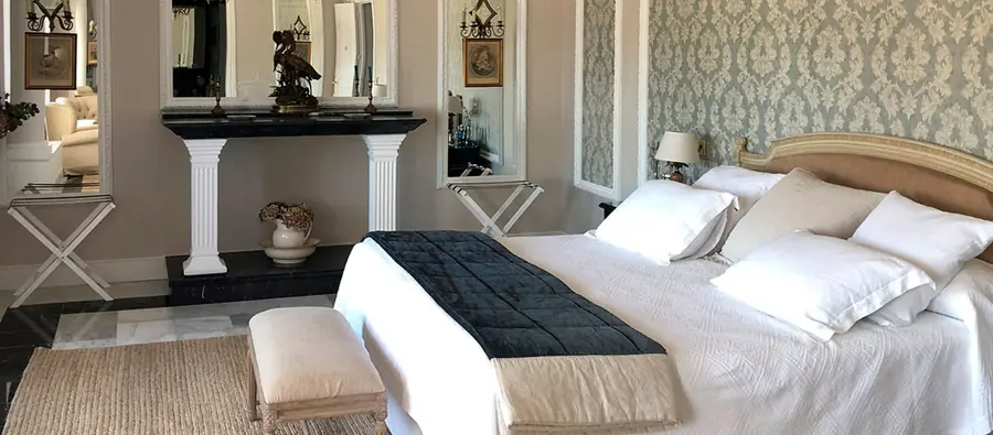 A bedroom at Ventosilla with damask wallpaper, a carved gilt headboard and a marble floor