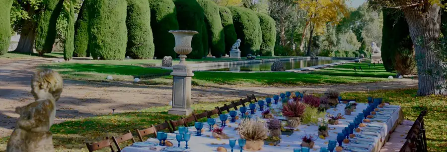 A long table laid on the lawn beside the canal at Ventosilla, among clipped yews and stone urns
